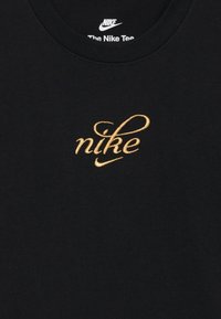 Melna kokvilnas t-kreklu ar zelta izšūtu "nike" logotipu un swoosh akcentu, apaļš kakla izgriezums un mīksta tekstūra.