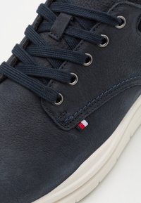 Marina lädersneakers med rund tå, strukturerad yta, metallöglor och marina snören. Har ett litet emblem i röd, vit och blå.