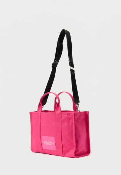 Ροζ καμβάς τσάντα ώμου με δύο επάνω χερούλια και ρυθμιζόμενο μαύρο λουρί. Περιλαμβάνει ετικέτα μπροστινού ενθέτου και τετράγωνο σχήμα, με ορατές ραφές.