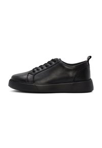 Black low-top leather sneaker with lace-up closure and thick rubber sole, showing the outer side view on a white background.