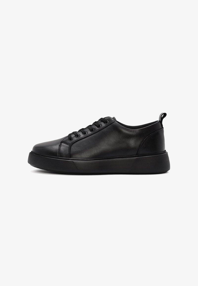 Zapatilla baja negra de piel con cierre de cordones y suela de goma gruesa, mostrando la vista lateral exterior sobre un fondo blanco.