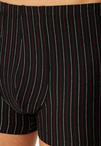 Boxer shorts noirs avec de fines rayures verticales rouges et blanches. Tissu doux avec une taille élastique et des détails de ourlet cousus.