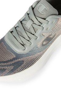 Szare plecione sneakersy z wzorzystym materiałem, jasnoszare sznurowadła oraz logo na wyściełanym języku i bocznej części, z białą podeszwą.