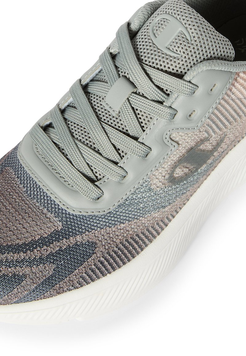 Zapatilla tejida gris con tela estampada, cordones gris claro y logotipo en la lengüeta acolchada y en el lateral, con una suela blanca.