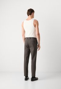 Men's outfit featuring a white ribbed tank top and gray tailored trousers. The pants have a sleek finish and side pockets. Black shoes complete the look.