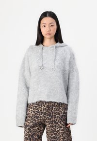 Grå, fluffig huva tröja med en beskuren design, med dragsko och silverfästen, matchad med leopardmönstrade byxor.