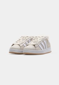 Lys grå semsket skinn sneakers med hvit tre-stripes design, flate snøring og en gummisåle. Har en teksturert overdel og polstret krage.