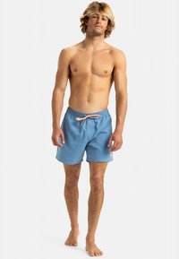 Lichtblauwe zwemshorts met een elastische tailleband en een roze trekkoord. Gemaakt van lichtgewicht, glad materiaal. Voorzien van een logo aan de zijkant.