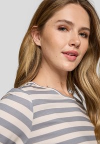 Gestreiftes langärmliges Hemd in Grau und Creme, mit runder Ausschnitt und weichem Stofftextur. Minimalistisches Design mit gleichmäßigen Mustern.