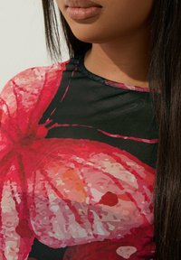 Musta verkko toppi, jossa on suuri, eläväinen kukkakuosi pinkin ja oranssin sävyissä, pyöreä kaula-aukko ja lyhyet hihat.