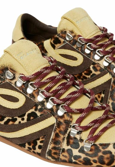 Zapatilla con ante amarillo y marrón, acentos de piel de leopardo y cordones con patrón color burdeos y ojales plateados.