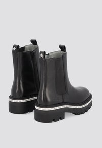 Czarne skórzane botki za kostkę z elastycznymi panelami bocznymi, zamkiem błyskawicznym i teksturowaną podeszwą. Posiadają białą markową taśmę wokół podstawy.