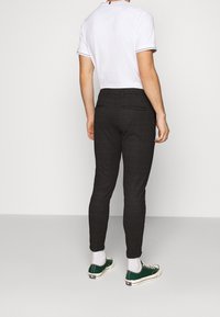 Czarne spodenki w kratkę o slim fit, z tylnymi kieszeniami. W zestawie z białą koszulką i zielonymi trampkami.