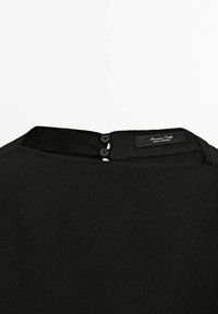 Czarna bluzka o gładkiej teksturze, okrągłym dekolcie i dwóch czarnych guzikach z tyłu. Metka brzmi "Massimo Dutti, wyprodukowano w Maroku."