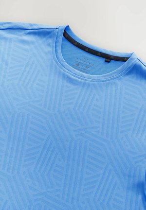 T-shirt actif bleu clair avec un motif géométrique texturé, col rond et accent noir à l'intérieur du col. Tissu doux et respirant.