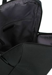 Interno di una borsa da viaggio nera con una texture liscia, dotata di una tasca con zip e di un ampio scomparto per l'organizzazione.