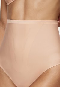 Majtki z wysokim stanem w kolorze nude, wykonane z gładkiej, elastycznej tkaniny; z subtelnym geometrycznym wzorem z przodu i bezszwowym paskiem w talii.
