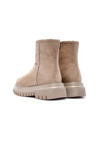 Botas de tobillo de ante beige con un acabado texturizado, puntera redondeada y una suela de goma gruesa con surcos. Diseño de bajo perfil con cremallera lateral.