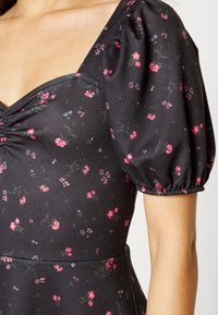 Vestido preto com estampado floral, com mangas bufantes, decote em V e padrões florais em rosa e branco. Tecido suave com um ajuste justo.