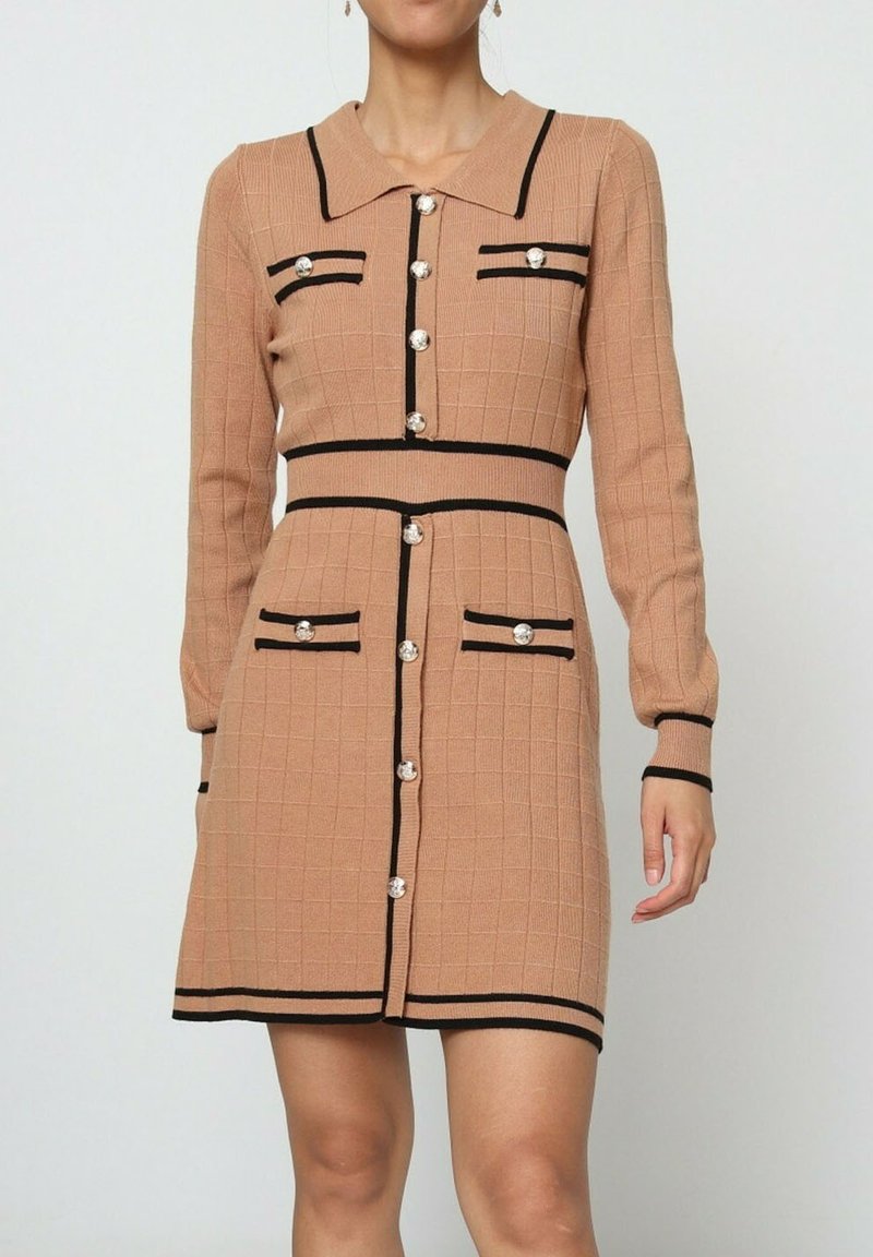 Robe tricotée marron clair avec un col, des accents noirs et quatre fausses poches, comportant des boutons argentés et une silhouette ajustée.
