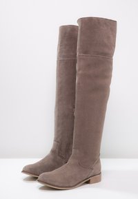 Botas sobre la rodilla de ante taupe con suela plana y ligero tacón, con cremallera lateral para facilitar su uso.