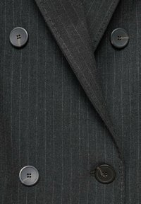 Giacca da abito doppiopetto grigio scuro con righe, quattro bottoni neri e rever a punta.