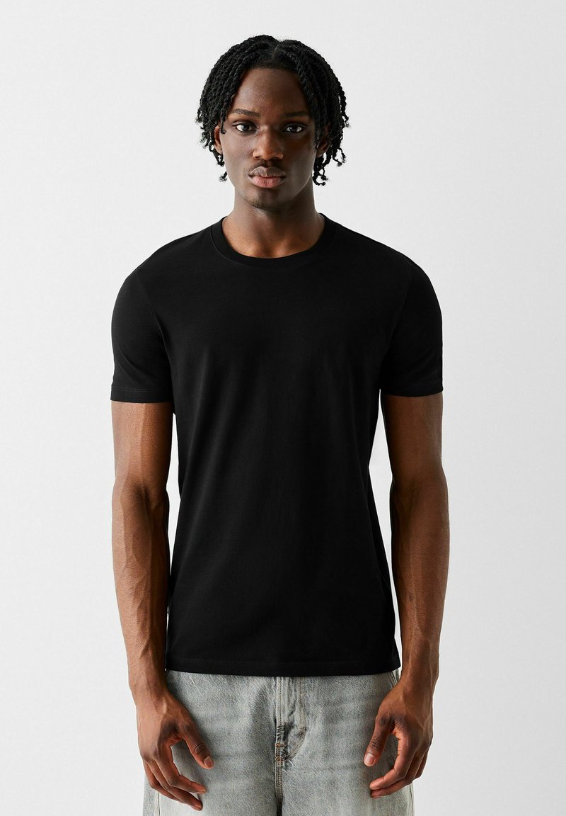 Black short-sleeved T-shirt in a smooth cotton fabric with a classic crew neckline, paired with light-wash jeans.