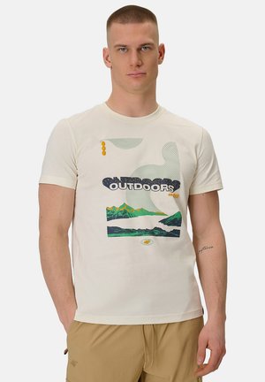 Mężczyzna w białej koszulce z grafiką krajobrazu górskiego i napisem "OUTDOORS", w połączeniu z beżowymi szortami na jednolitym tle.