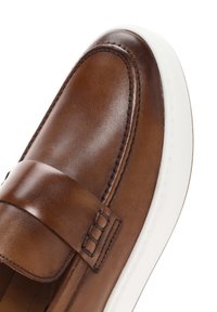 Zapato de cuero marrón con un diseño sin cordones, que presenta una banda plana, suela blanca y detalles de costura visibles.
