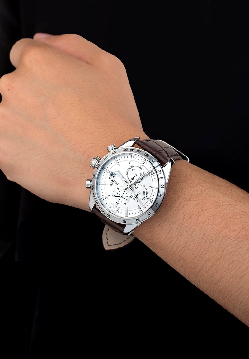 Reloj cronógrafo plateado con una esfera blanca y correa de cuero marrón, que presenta múltiples subesferas y una pantalla de fecha.