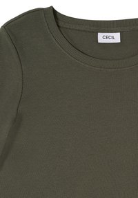 Haut en tissu côtelé vert olive avec encolure ronde et étiquette de marque CECIL cousue à l'intérieur du col.
