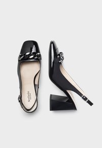 Czarne lakierowane buty slingback z kwadratowym noskiem, zdobione łańcuszkiem, na masywnej obcasie. Gładka tekstura i regulowany pasek na kostkę.