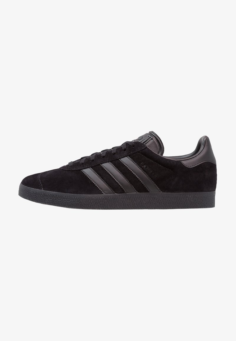 Schwarze Wildleder-Sneaker mit schwarzen Lederakzenten, ausgestattet mit drei charakteristischen Streifen, strukturiertem Gummisohle und klassischem Low-Top-Design.