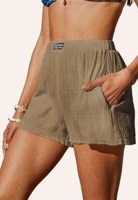 Shorts kaki en tissu texturé, avec une coupe décontractée, une taille élastique et des poches latérales pour plus de fonctionnalité.