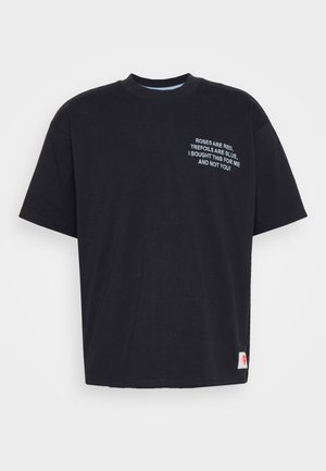 Schwarzes Baumwoll-T-Shirt mit kurzen Ärmeln und rundem Ausschnitt. Mit weißem gesticktem Text auf der Vorderseite, der einen verspielten Spruch zeigt.