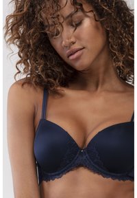 Navy blue pehmeä rintaliivi, jossa on pitsireunus kuppeissa, säädettävät olkaimet ja pieni yksityiskohta keskellä. Sileä kangas.