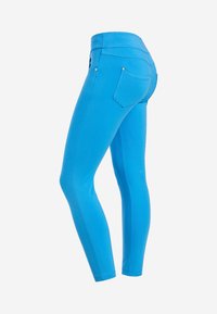 Jeans attillati in tessuto blu brillante con una texture liscia. Caratterizzati da un'alta vita, due tasche posteriori e dettagli con bottoni argentati.