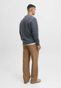 Gray knitted sweater with a round neckline, ribbed cuffs, and hem, paired with tan wide-leg trousers and light-colored footwear.