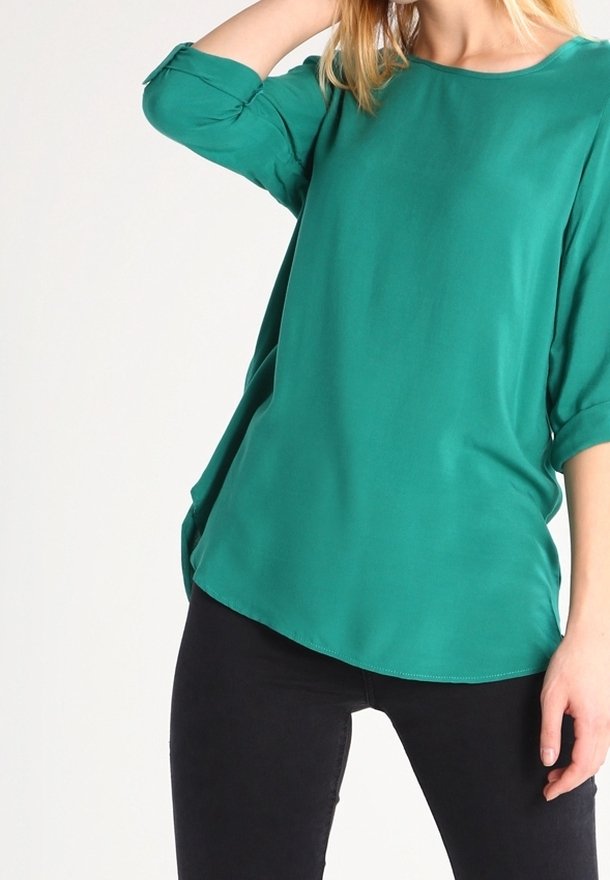 Blusa verde, leggera, con scollatura rotonda e maniche a tre quarti. Presenta una vestibilità ampia e un'orlo curvo. Tessuto morbido.