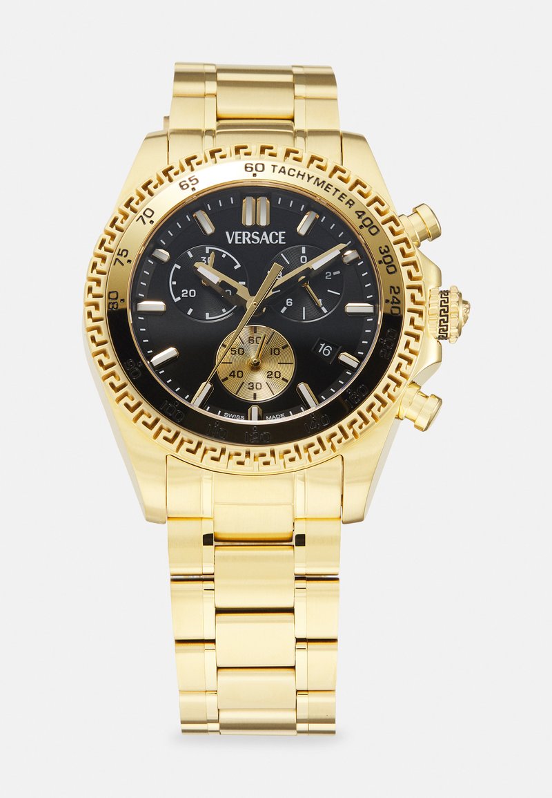 Arany fém karkötő óra fekete számlappal, krónográf funkciókkal és bonyolult görög kulcs mintázattal a kerületen. Rozsdamentes acél lánc.