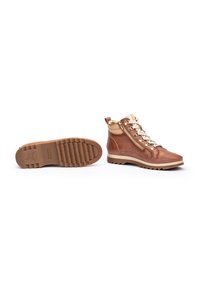 Botas de senderismo de cuero marrón con un tobillo alto, cordones blancos, cremallera lateral, suela de goma y patrón de agarre texturizado en la parte inferior.