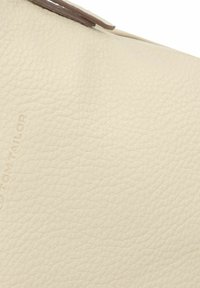 Sac à main en cuir texturé couleur crème avec un accent lisse et foncé le long du bord supérieur et une marque discrète sur la surface.