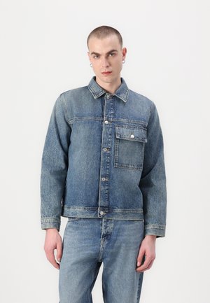 Lys blå denimjakke med knappelukking foran, spiss krage, brystlomme og avslappet passform. Teksturert stoff med falmede detaljer.