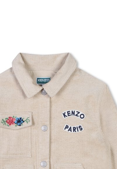 Veste en velours côtelé beige avec col, boutons en métal argenté, broderie florale sur la poche et écussons "KENZO PARIS" sur la poitrine.