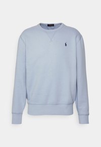 Světle modrá mikina vyrobená z m ěkkého materiálu, s kulatým výstřihem, žebrovanými manžetami a malým tmavým logem na levé hrudi.