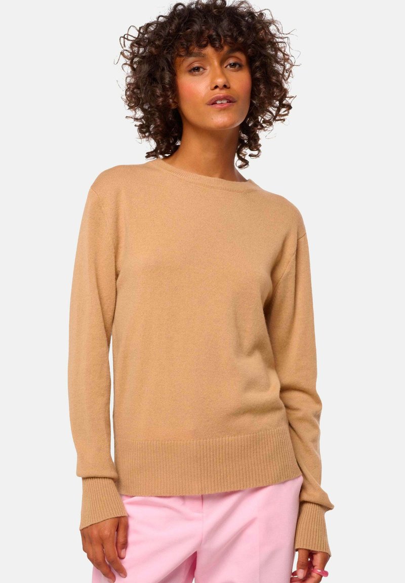 Helle beige Langarm-Software mit gerippten Bündchen und Saum, aus einem weichen, strukturierten Material gefertigt; kombiniert mit rosa Hosen.