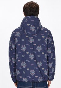 Jachetă cu model marin, având grafice colorate cu fețe, ochelari de soare și băuturi. Design cu glugă, cu manșete elastice și tiv inferior.