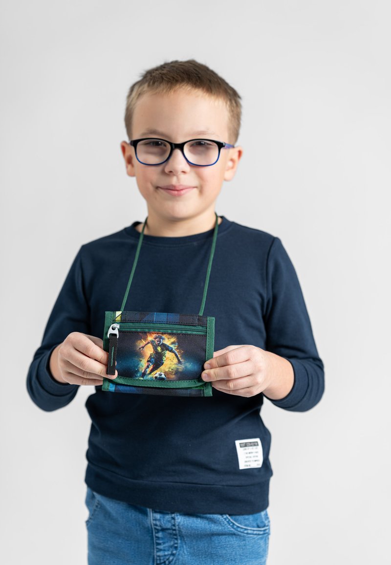 Green, fabric pouch with a zipper and a sports graphic, held by a child wearing a navy shirt and blue jeans. Features green cord for wearing.
