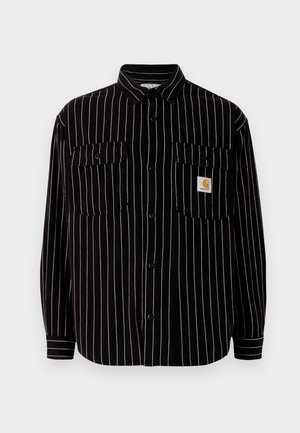 Chemise noire à manches longues avec des rayures verticales blanches, dotée d'un col étalé, de deux poches sur la poitrine et d'un petit logo.