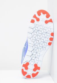 Suela de zapatilla deportiva morada con un patrón hexagonal blanco y detalles en naranja. Goma texturizada para mayor agarre y durabilidad.